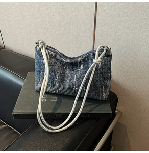Detail of blue sequin denim shoulder bag with silver rope straps and knot accents