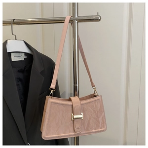 Detailed view of pink baguette bag featuring unique pleated leather texture and gold buckle