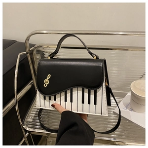 Detail of piano keyboard print handbag with golden treble clef metal hardware clasp