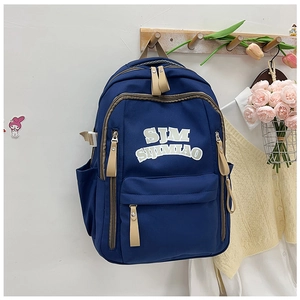 Detail of navy nylon backpack with SJM logo, leather pullers, and side pockets on wood hook