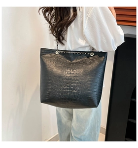 Close-up of black crocodile pattern faux leather texture with chain shoulder strap