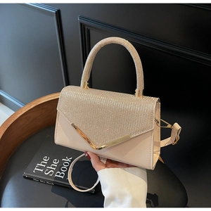 Detail of beige rhinestone clutch with V-shaped gold metal trim and leather strap