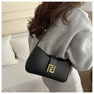 Minimalist black leather underarm bag with gold metal buckle shown on a model