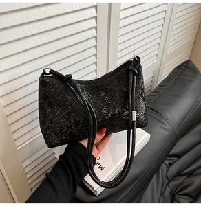 Close-up of black snake embossed leather underarm bag with zipper and slim shoulder strap