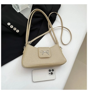 Detail view of beige fabric handbag with silver metal bow and smartphone size reference