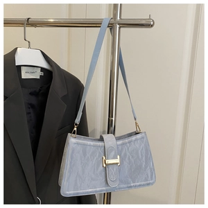 Detail of light blue crinkled baguette bag with gold buckle on a stylish hanger