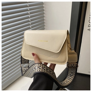 Detail of cream flap square bag with gold lettering and patterned jacquard wide strap