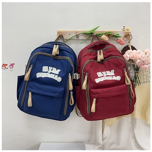 Navy and maroon nylon backpacks with front zipper pockets hanging on a wooden wall rack