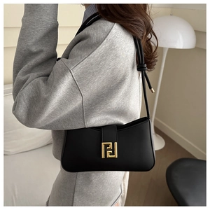Close-up of elegant black faux leather shoulder bag with decorative gold metal clasp