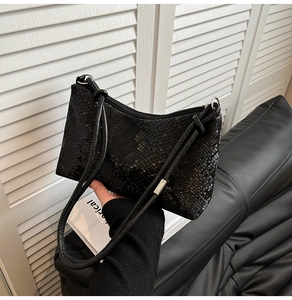 Detail of black faux snakeskin shoulder bag featuring refined scale texture and silver zipper