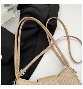 Close-up of beige straw woven texture shoulder bag with silver adjustable metal buckle