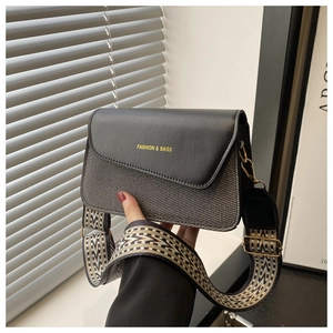 Detail of grey woven shoulder bag with black leather flap and ethnic jacquard strap