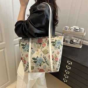 Fashionable floral jacquard tote bag with white leather straps worn by a female model