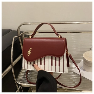 Detail of piano key pattern handbag with golden treble clef clasp and burgundy leather trim