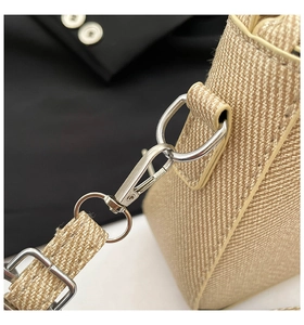 Close-up of silver metal hooks and D-rings on a beige woven shoulder bag handle