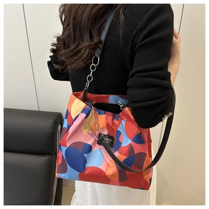 Close-up of vibrant printed tote bag featuring metallic chain strap and logo patch