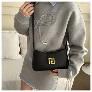 Close-up of matte black leather handbag featuring a minimalist gold geometric metal lock