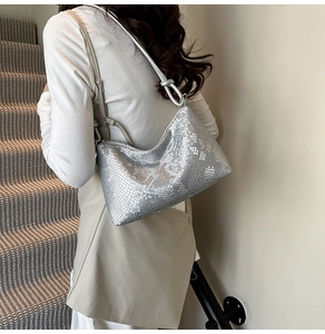 Detail showing the silver faux-snakeskin texture and knot design of the underarm bag