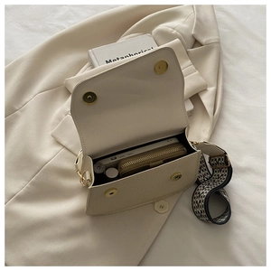 Detail view of beige square bag interior with geometric strap and magnetic closure