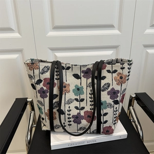 Fashionable large woven tote bag with colorful floral patterns and black leather straps