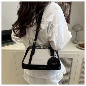 Detail view of canvas and leather contrast tote bag with round charm and zipper