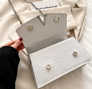 Detail showing white crocodile leather texture with silver V-logo and dual magnetic clasp