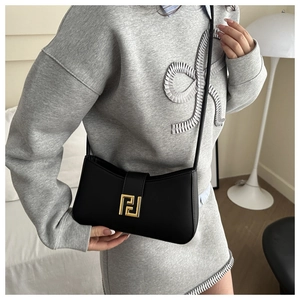 Detail of black leather half-moon bag featuring a shiny gold geometric metal buckle