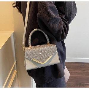 Detail of grey mini crossbody bag with glittering silver rhinestones and gold V-trim
