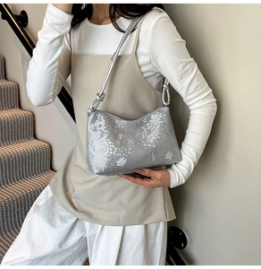 Detail of silver snake-embossed shoulder bag with knotted strap and metallic finish