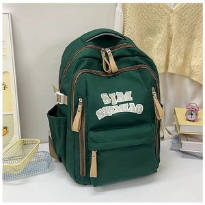 Detail of forest green nylon backpack with SJM logo, zipper pockets and side water bottle pouch