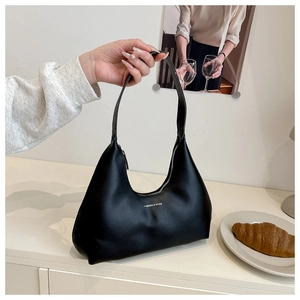 Detail of a black crescent shoulder bag with white Fashion & Bags text on its leather surface