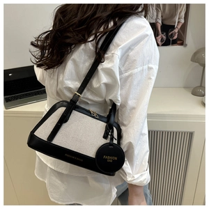 Close-up of canvas and black leather shoulder bag with Fashion & Bags metal pendant