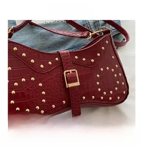 Gros plan sur le sac croissant bordeaux en cuir façon crocodile avec rivets dorés