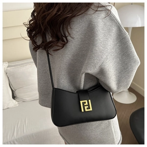 Close-up of black leather rectangular shoulder bag with elegant gold geometric metal buckle