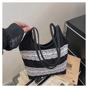 Détail d'un sac cabas noir avec rayures en dentelle florale blanche et doubles anses