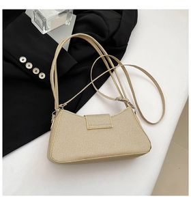 Detailed close-up of the textured beige baguette bag with a minimalist flap and slim strap