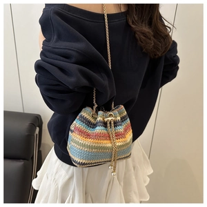 Detail of colorful woven bucket bag with gold chain strap and elegant pearl accents