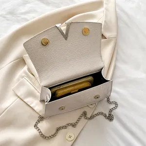Macro shot of white croc-embossed leather bag showing spacious interior with silver V-clasp