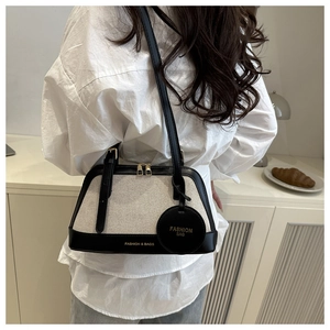 Detail showing canvas tote with black leather trim and gold zipper on a model