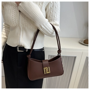 Detailed view of brown leather shoulder bag with gold geometric buckle and knot strap