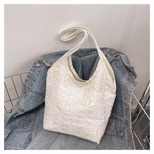Vue détaillée de la texture en dentelle florale blanche d'un grand sac cabas