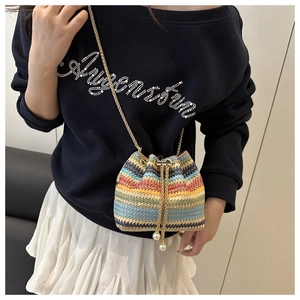 Detail view of colorful woven bucket bag with pearl drawstring charms and chain strap