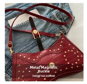 Détail du sac rouge à texture crocodile avec rivets dorés et fermoir magnétique