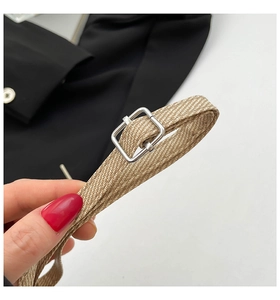 Macro detail of khaki woven strap featuring a polished silver square metal buckle closure