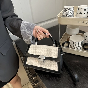 Petit sac beige tissé avec bordure en cuir noir et fermoir rotatif en métal argenté