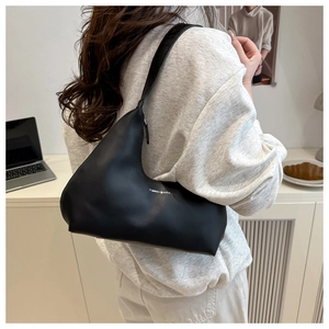Chic black asymmetrical moon bag styled with lifestyle items for a modern city look