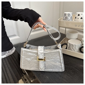 Detail of silver baguette bag with metallic pleated texture and golden metal buckle