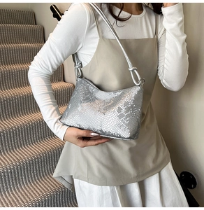 Detail of silver snake-print shoulder bag with metal rings and zipper closure