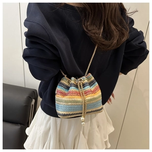 Detailed shot of rainbow woven bucket bag with pearl drawstring and gold chain strap