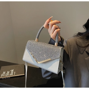 Detail of white leather bag featuring sparkling rhinestone handle and gold metal V-trim